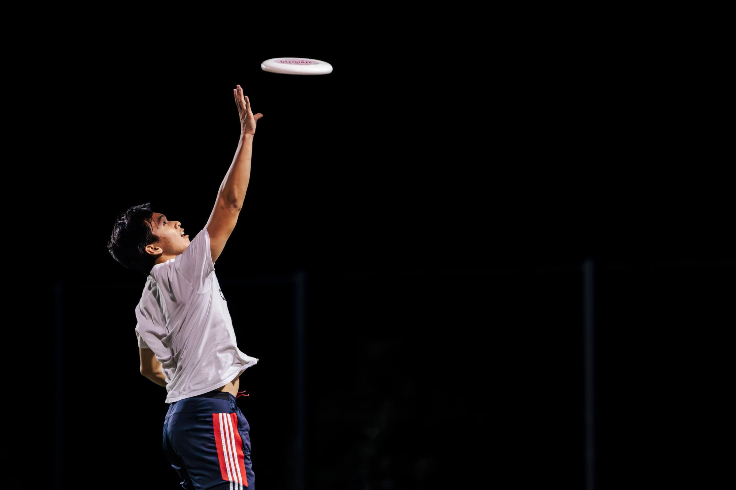 A night sports scene with a flying disc under stadium light.