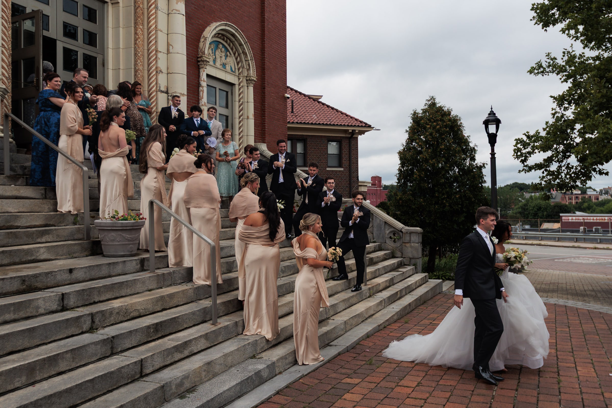 Chiara and Mirgen walk from the church as the wedding party gathers on the steps.
