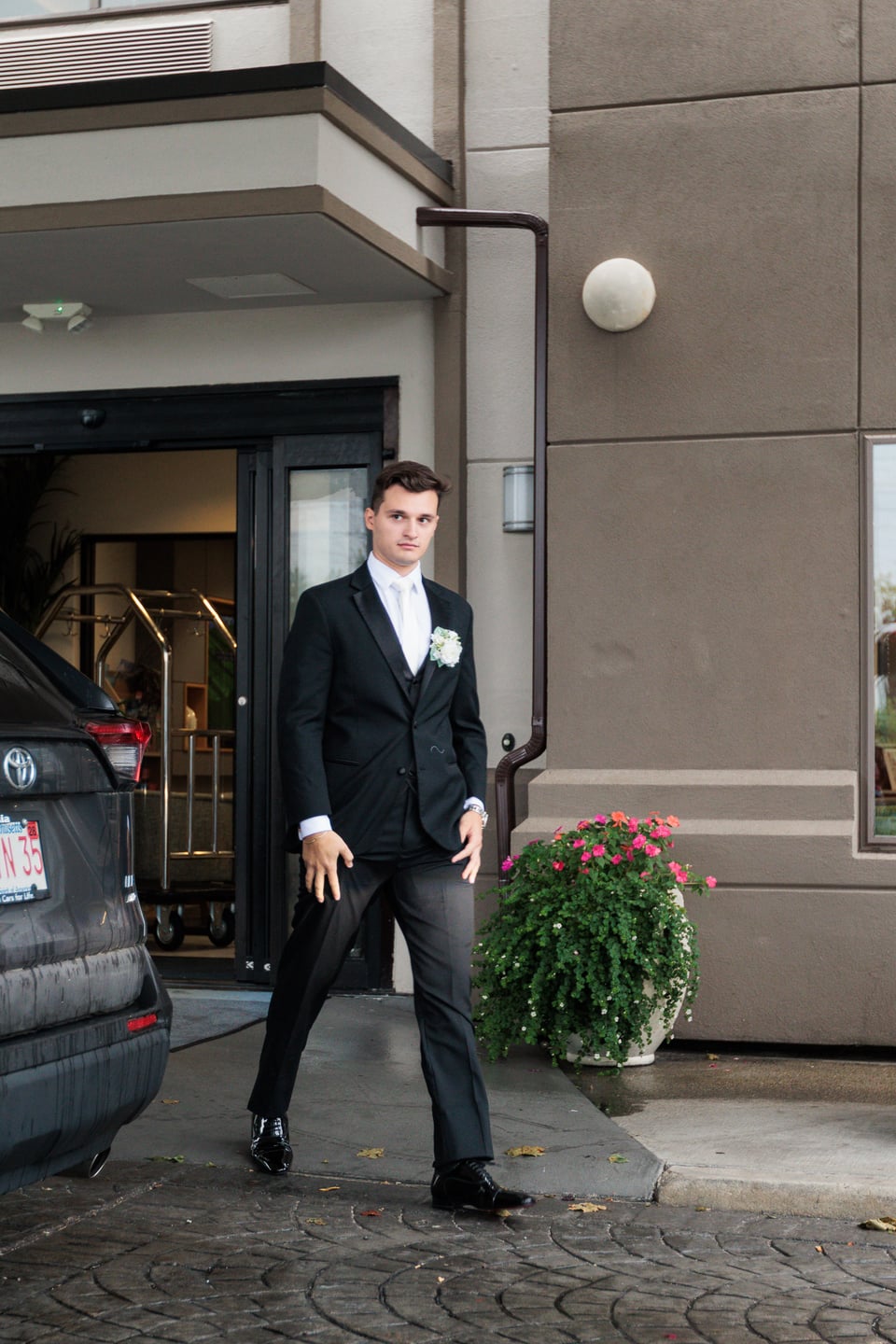 A man in a dark suit steps outside as the wedding party departs.