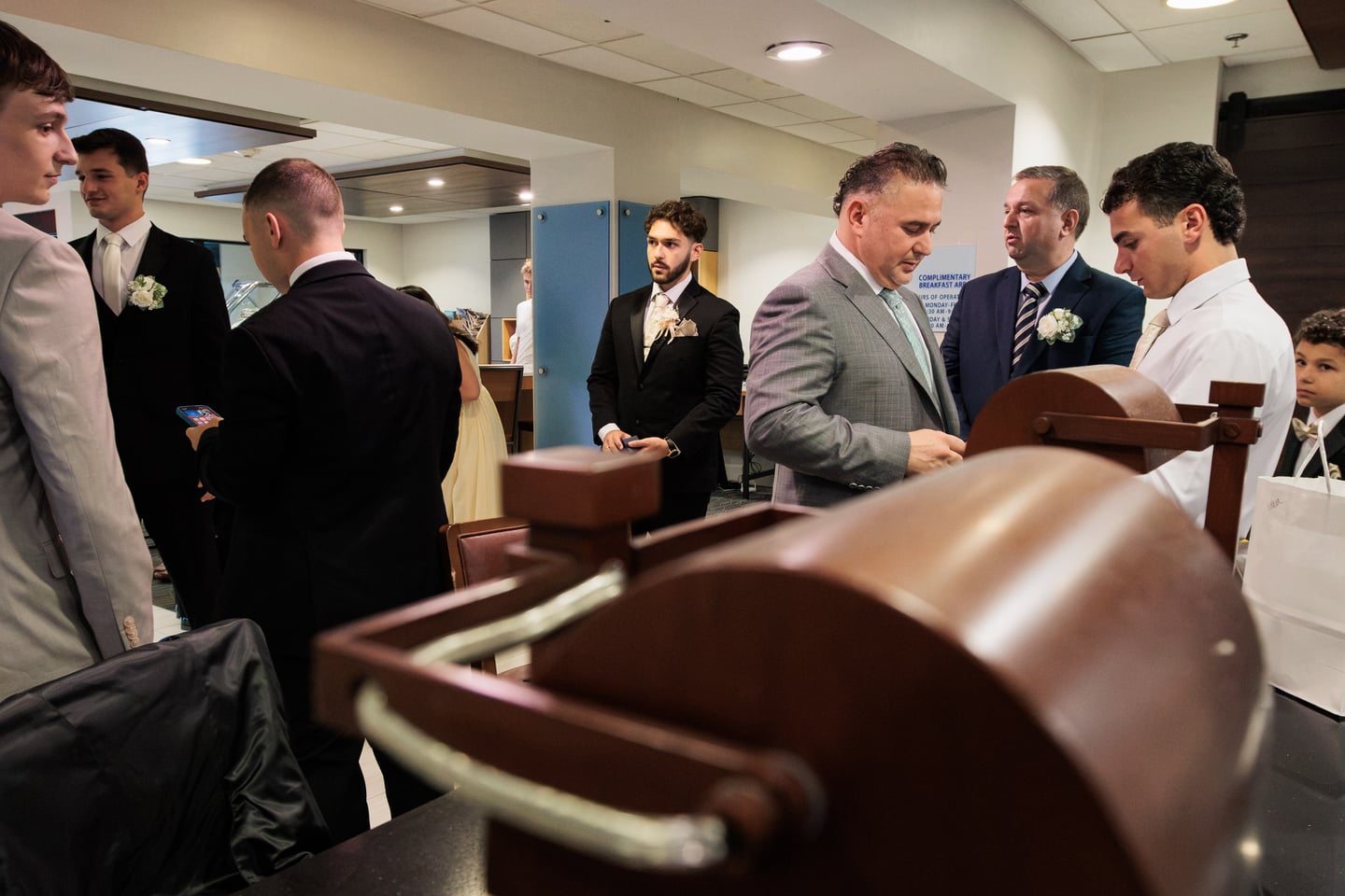 Members of the wedding party gather around a chair during preparations.