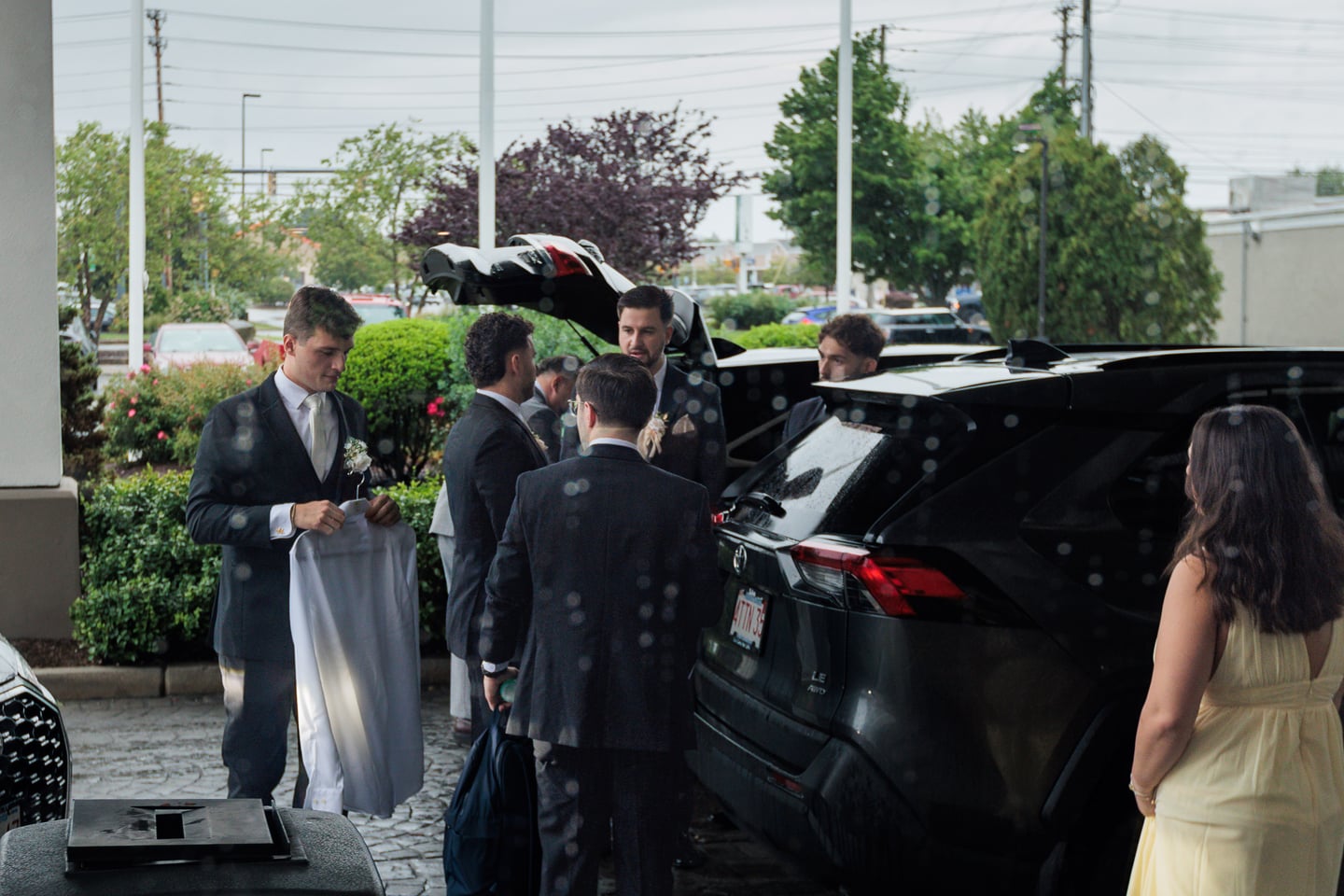 Members of the wedding party gather beside a car before leaving for the ceremony.