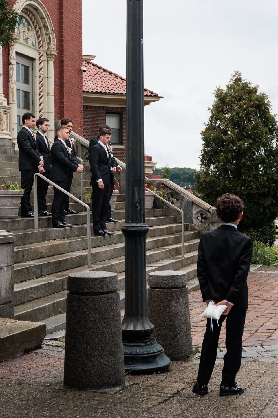 A man in formalwear waits near the church steps and entrance.
