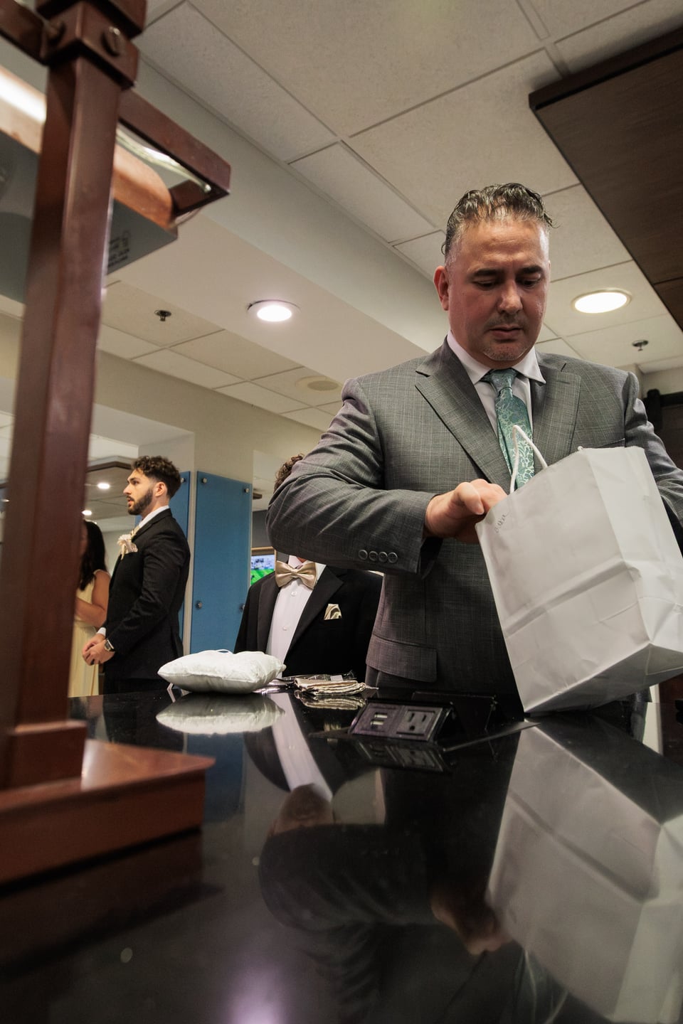 A man in a gray suit adjusts his jacket during wedding preparations.