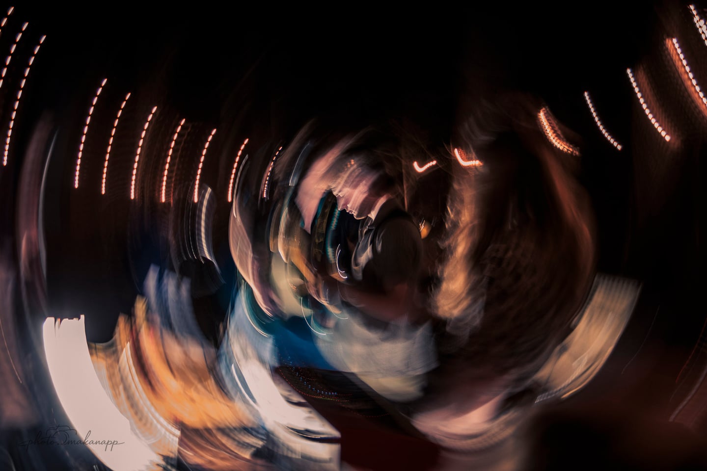 A swirling long exposure turns the performers and string lights into curved trails of motion.