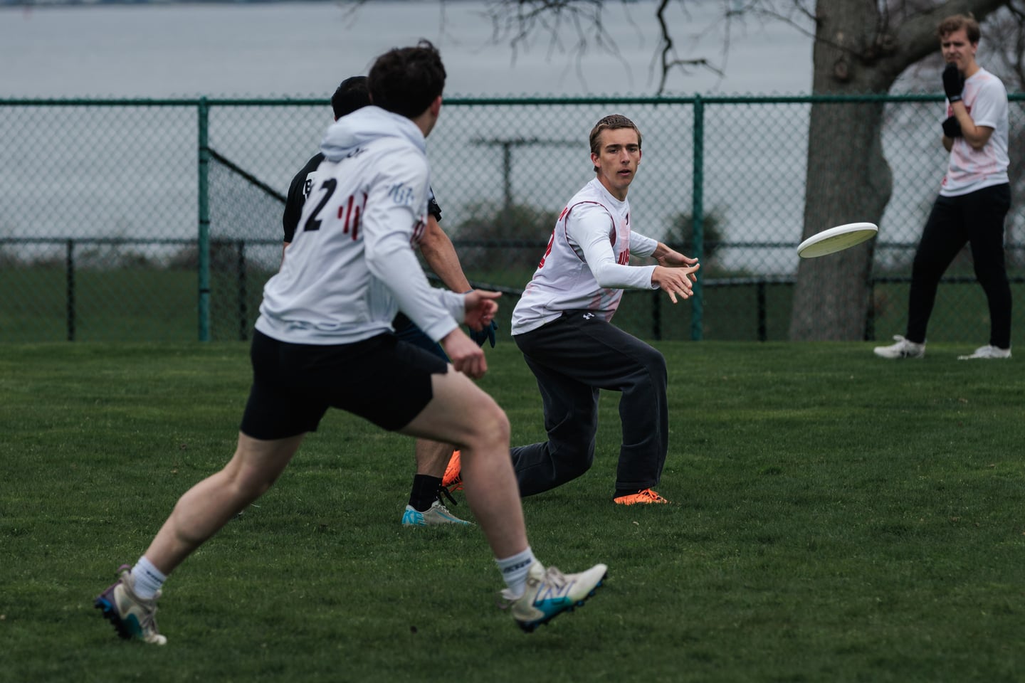 White-clad player receives a chest-high disc as teammates converge.