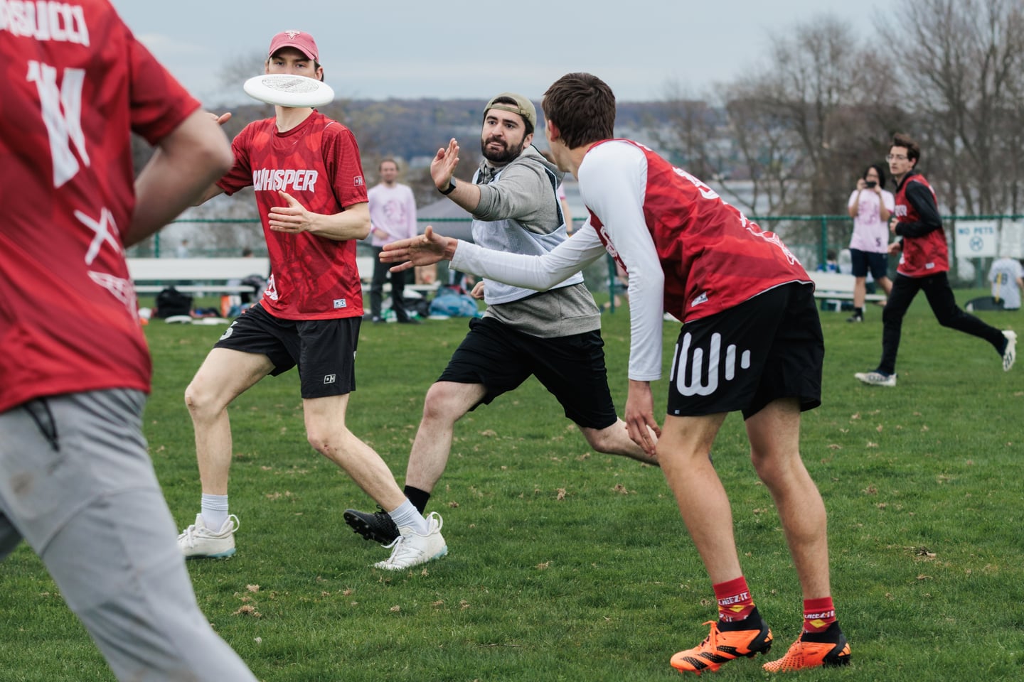 Red-clad teammates exchange a short pass around a gray-clad defender.