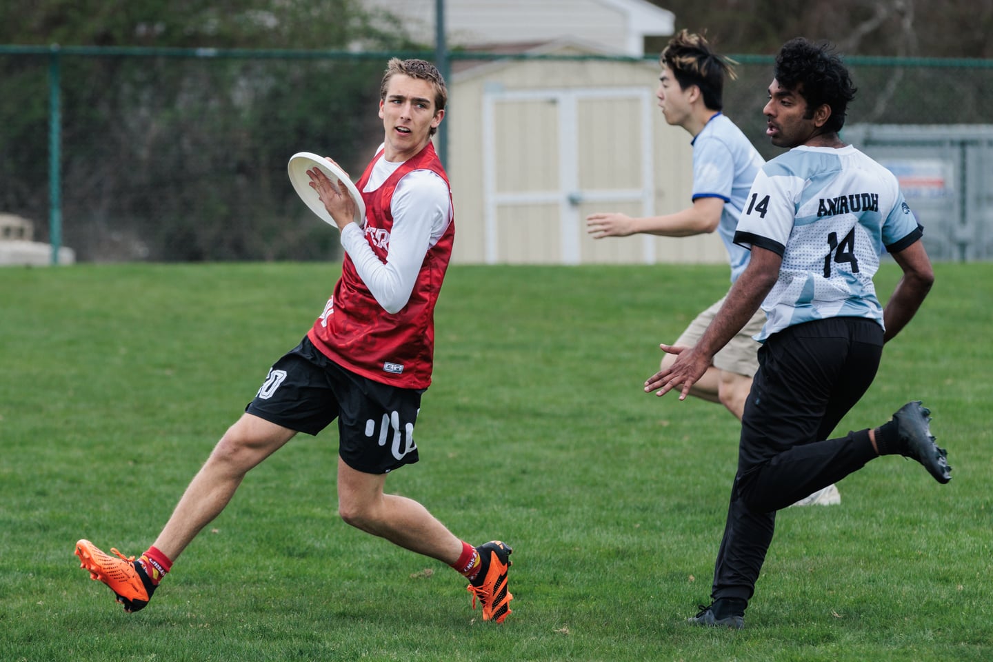 Red-clad handler pivots with the disc against a close gray-clad mark.