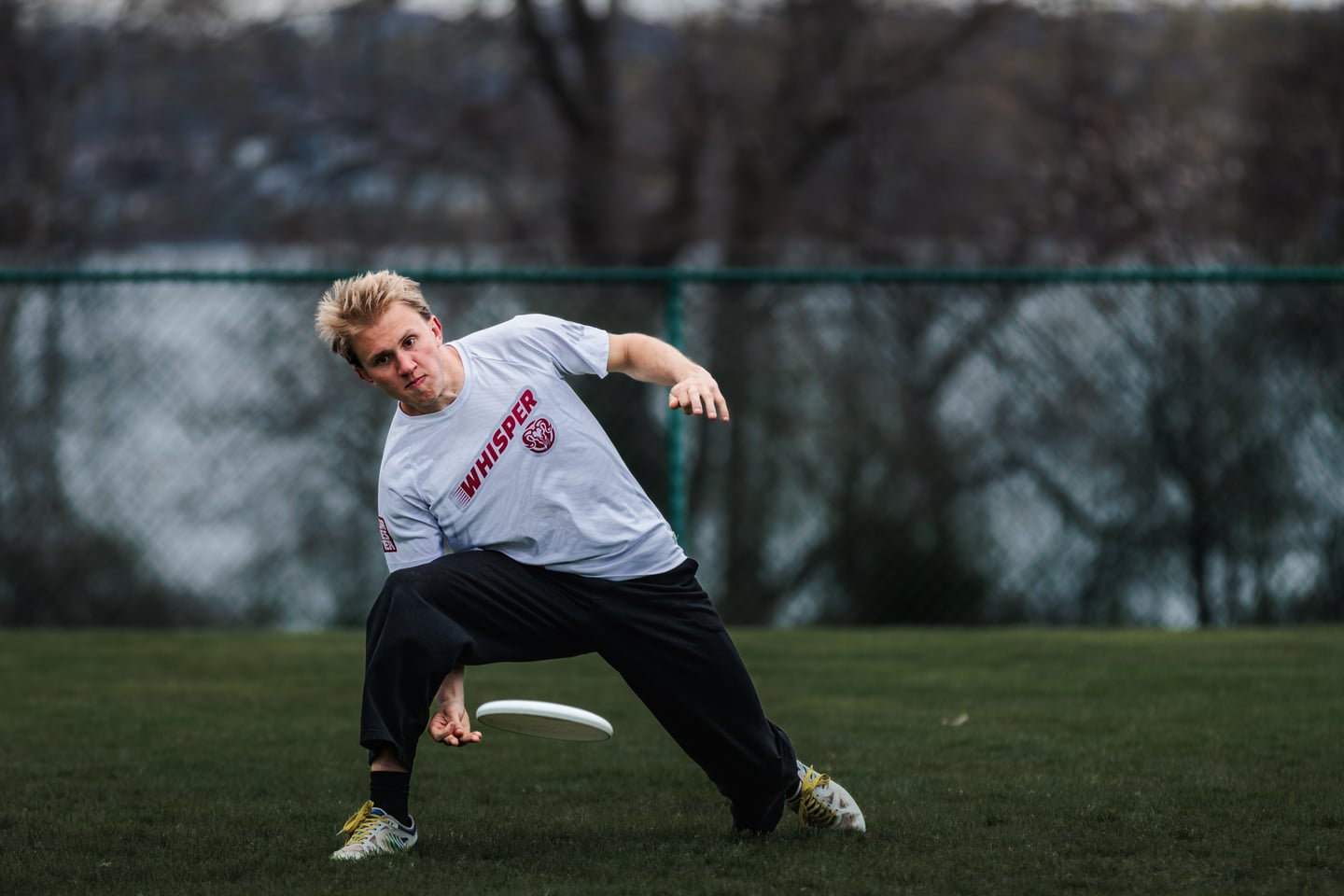 White-clad handler leans into a low release while moving across the field.