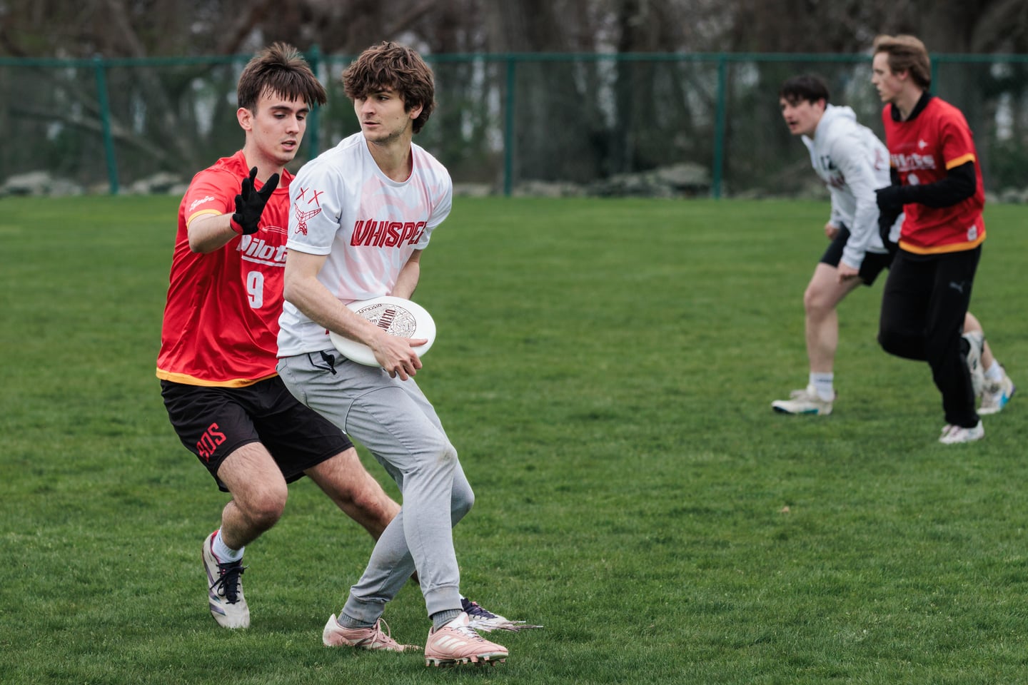 White-clad handler protects the disc from a close red-clad marker.