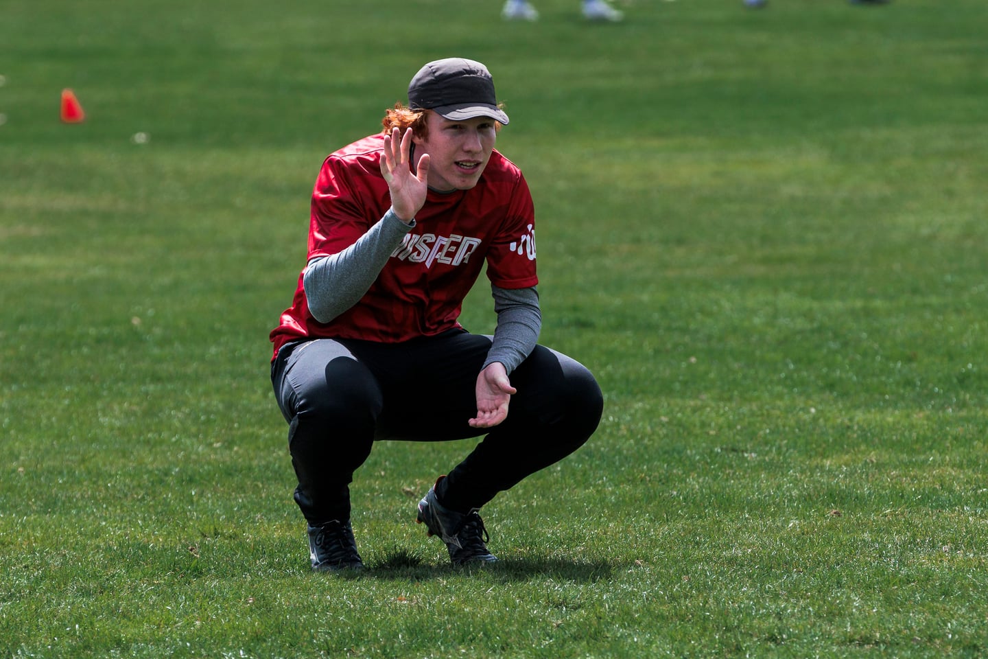 Red-clad player crouches on the field between points.