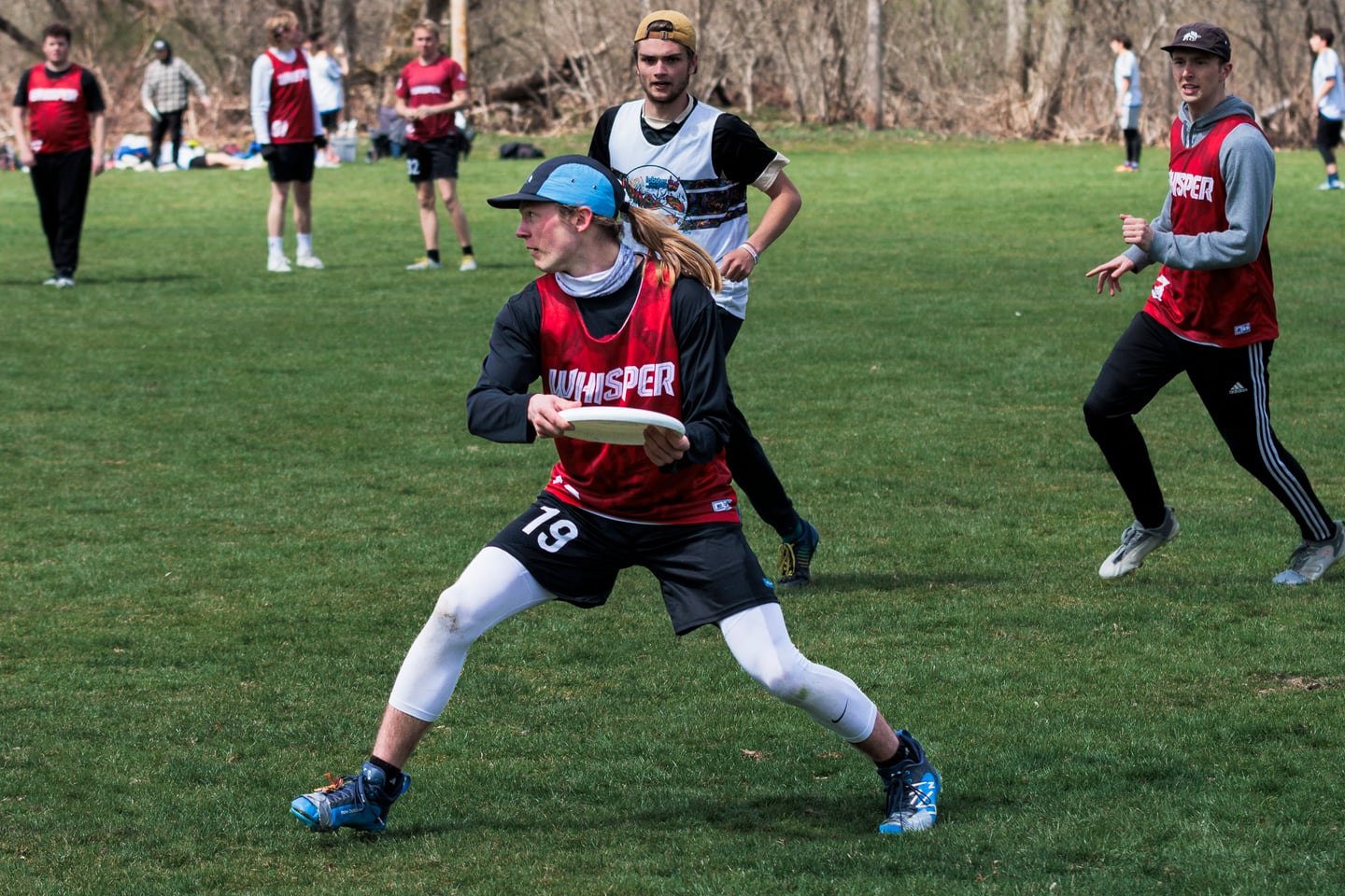 Red-clad handler pivots with the disc while teammates move downfield.