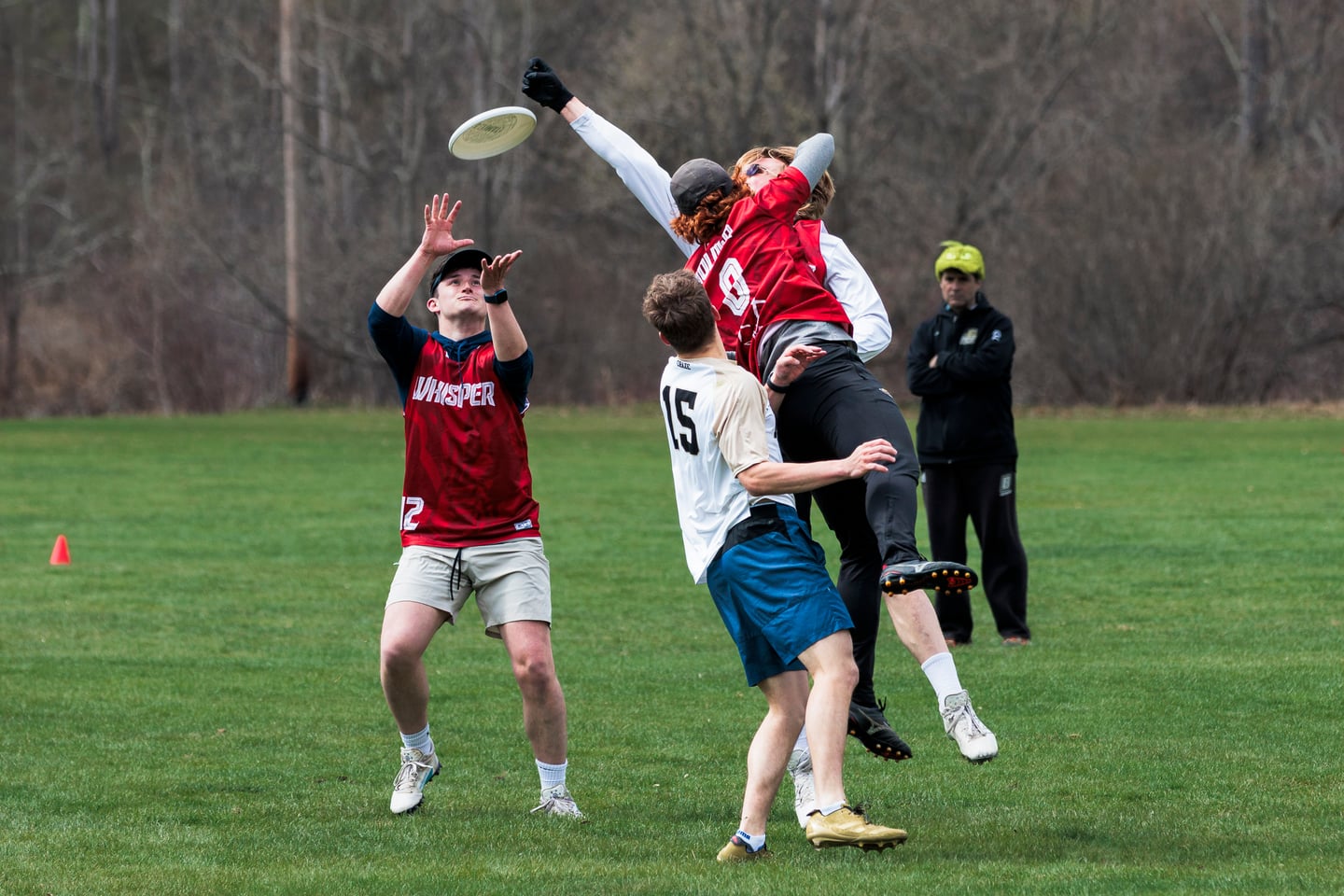 Two ultimate players contest a high disc above the field.