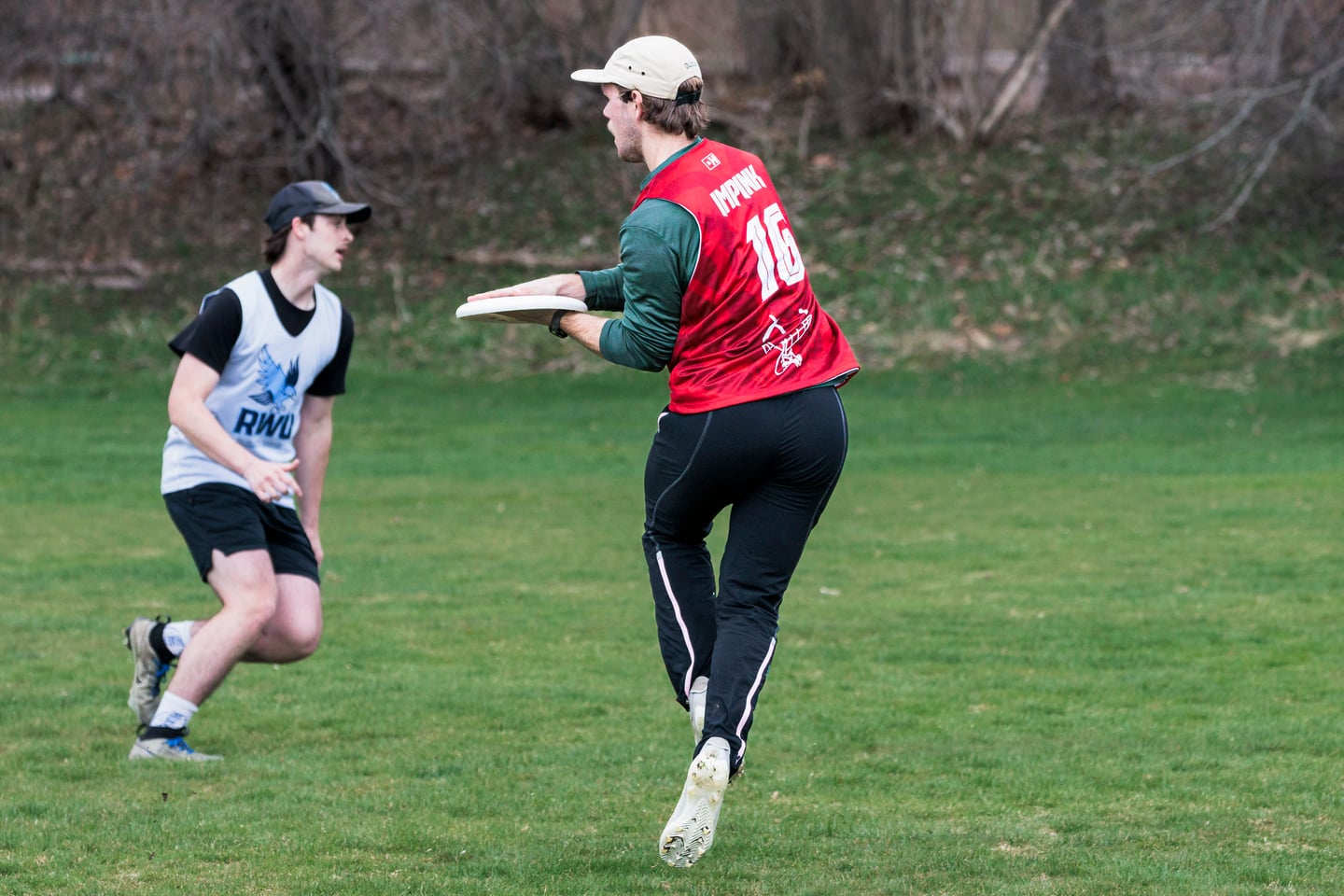 Red-clad handler holds the disc against a close defensive mark.