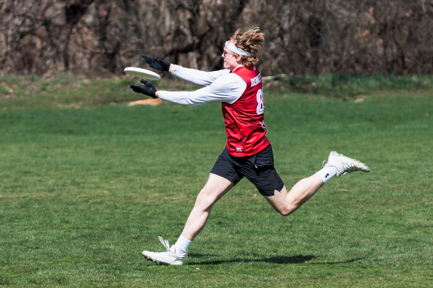 Red-clad player extends forward while running across the field.