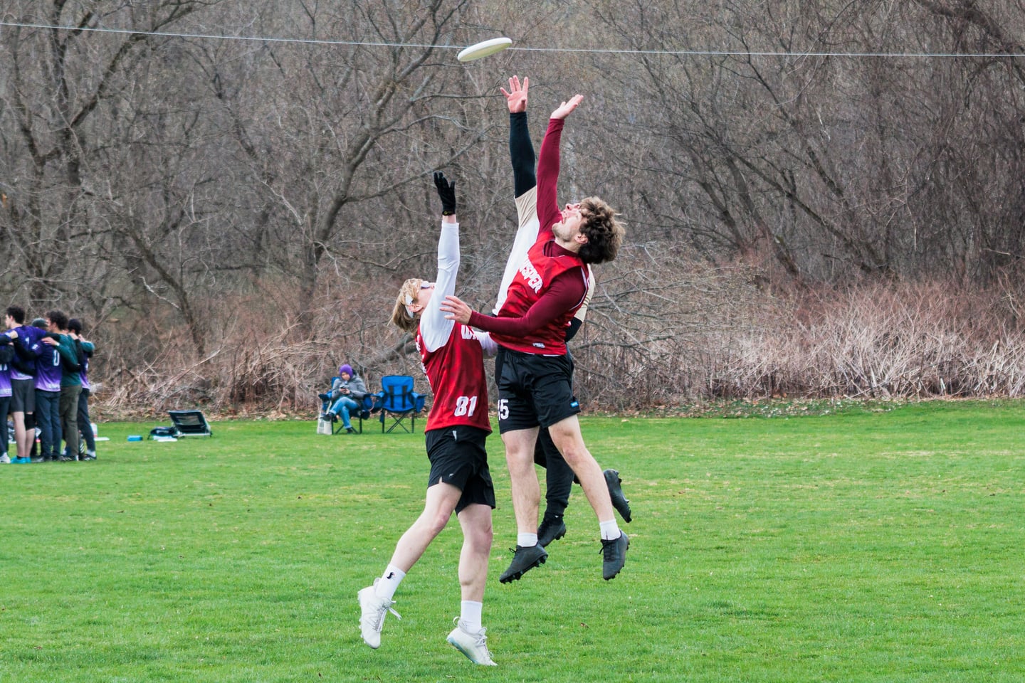 Red and gray-clad players jump together for a contested disc.