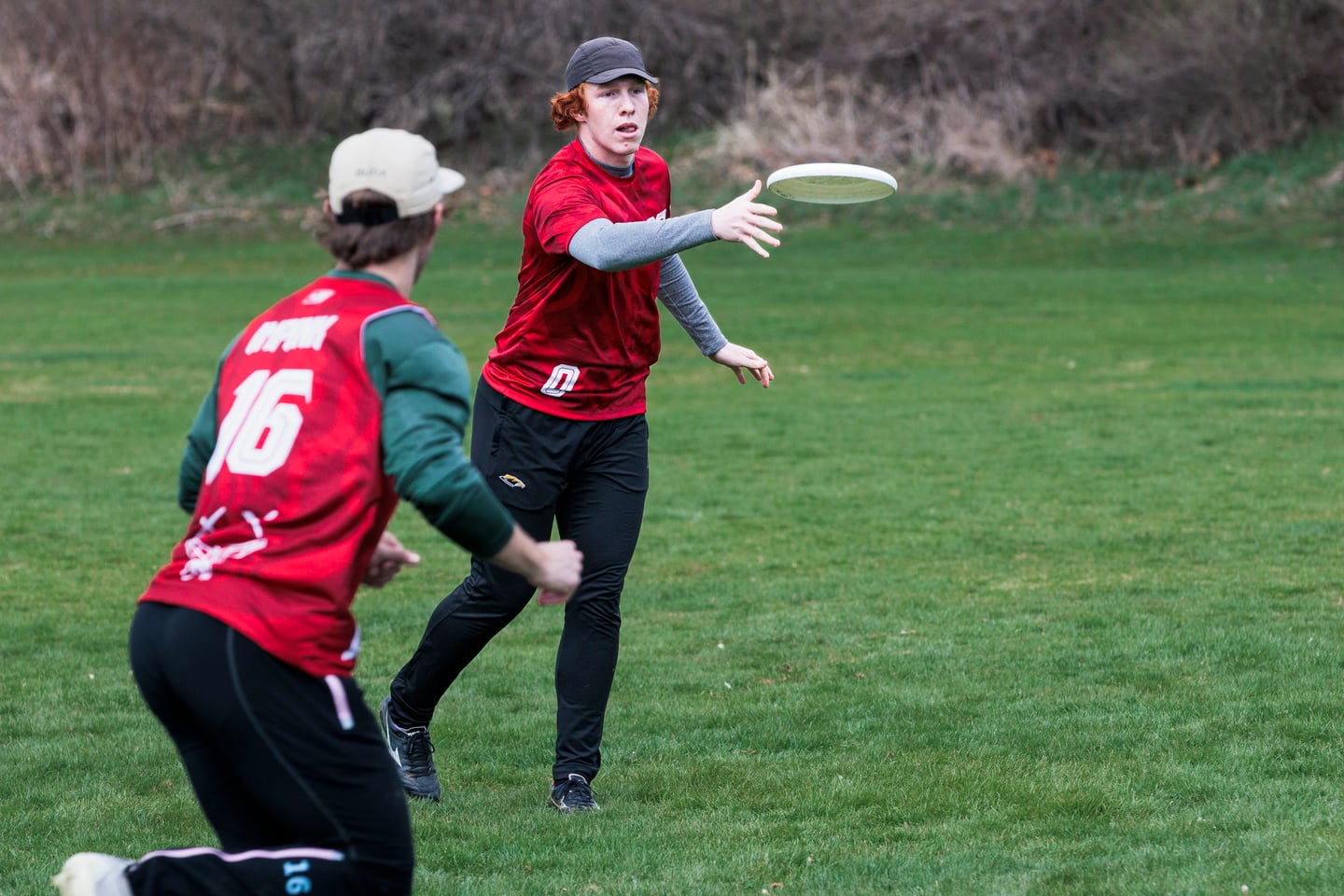 Red-clad player throws to a teammate moving across the field.