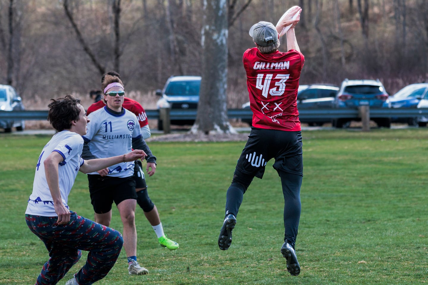 Red-clad player rises above defenders to reach for the disc.