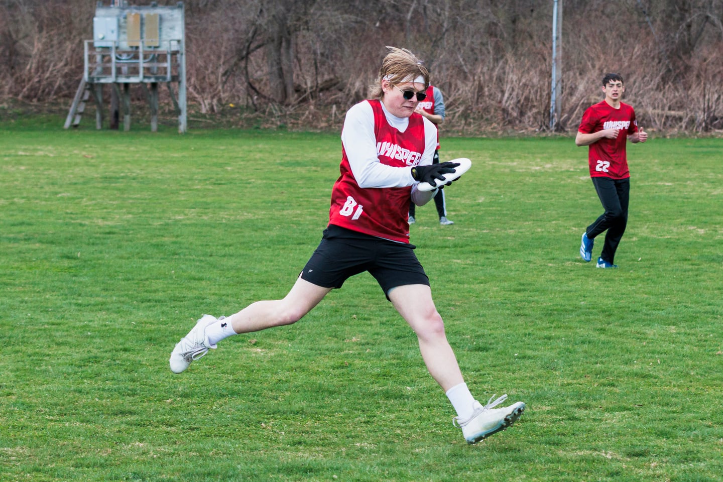 Red-clad ultimate player sprints across the grass during a point.