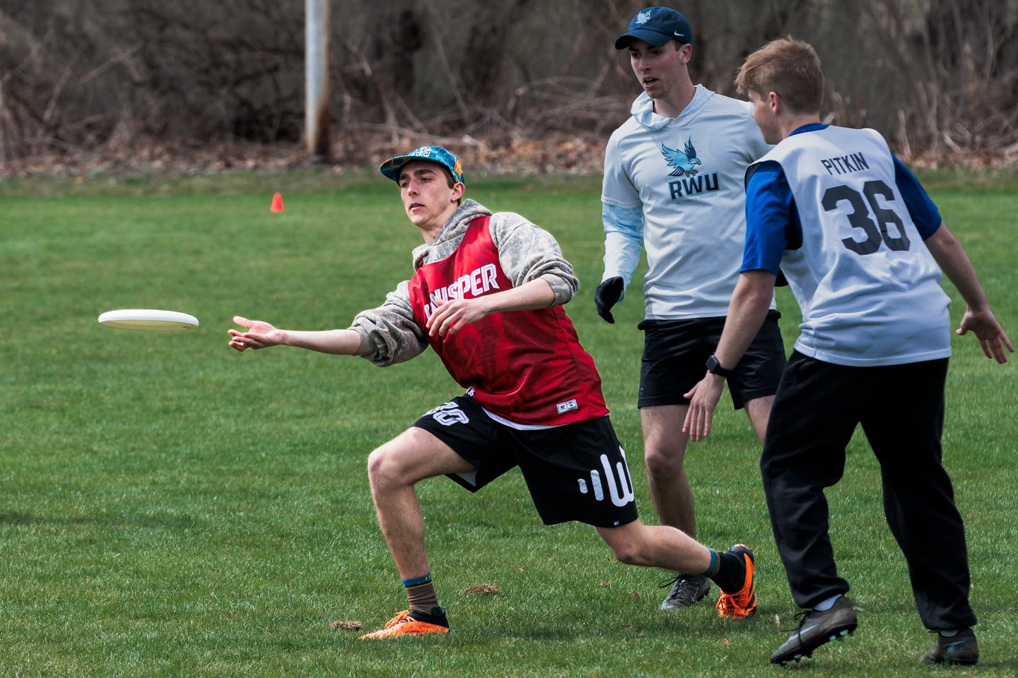 Red-clad handler releases a low throw around a defender.