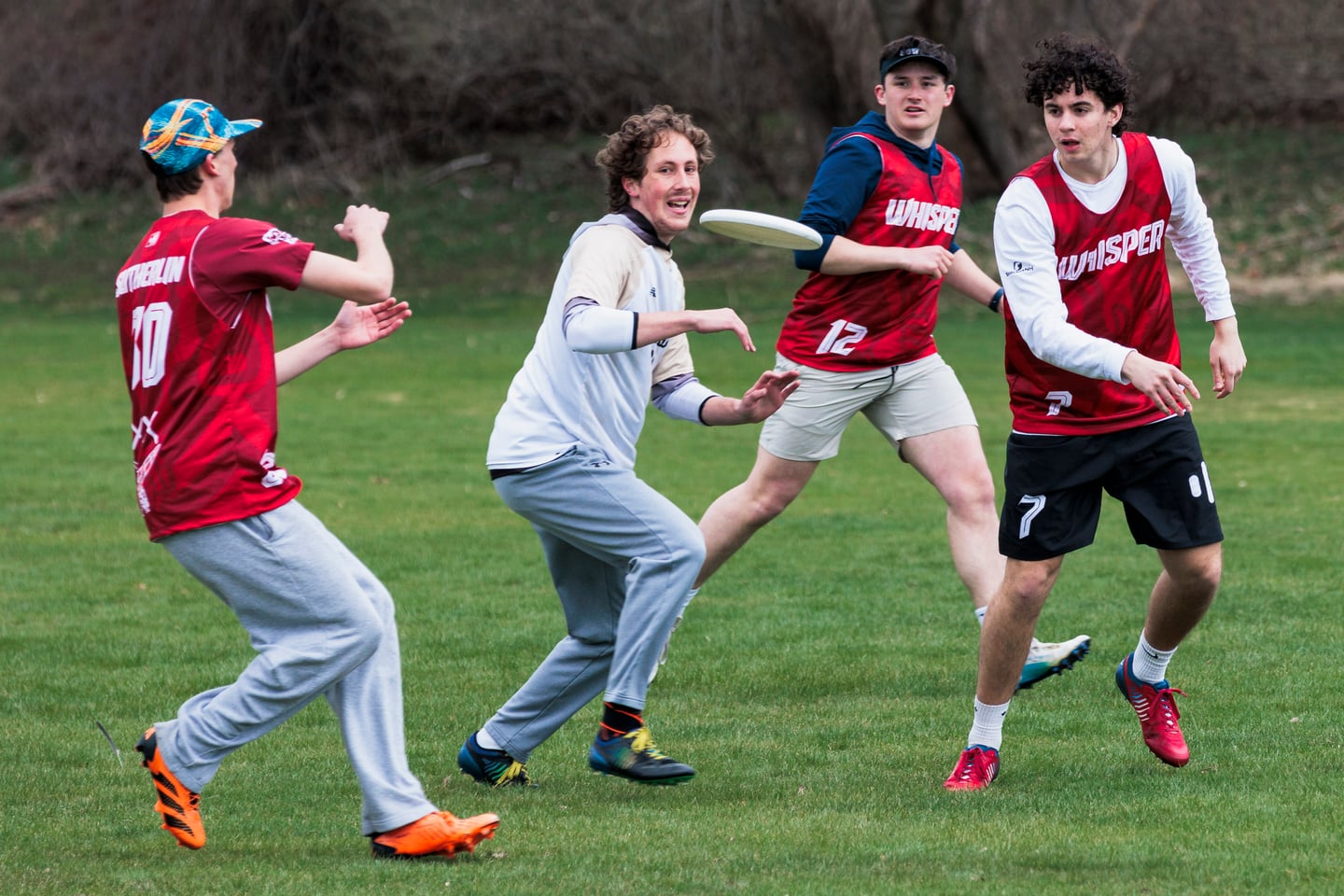 Red-clad ultimate player handles the disc while two gray-clad defenders close in.