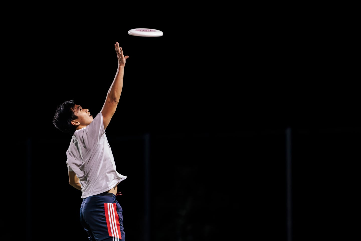 A night sports scene with a flying disc under stadium light.