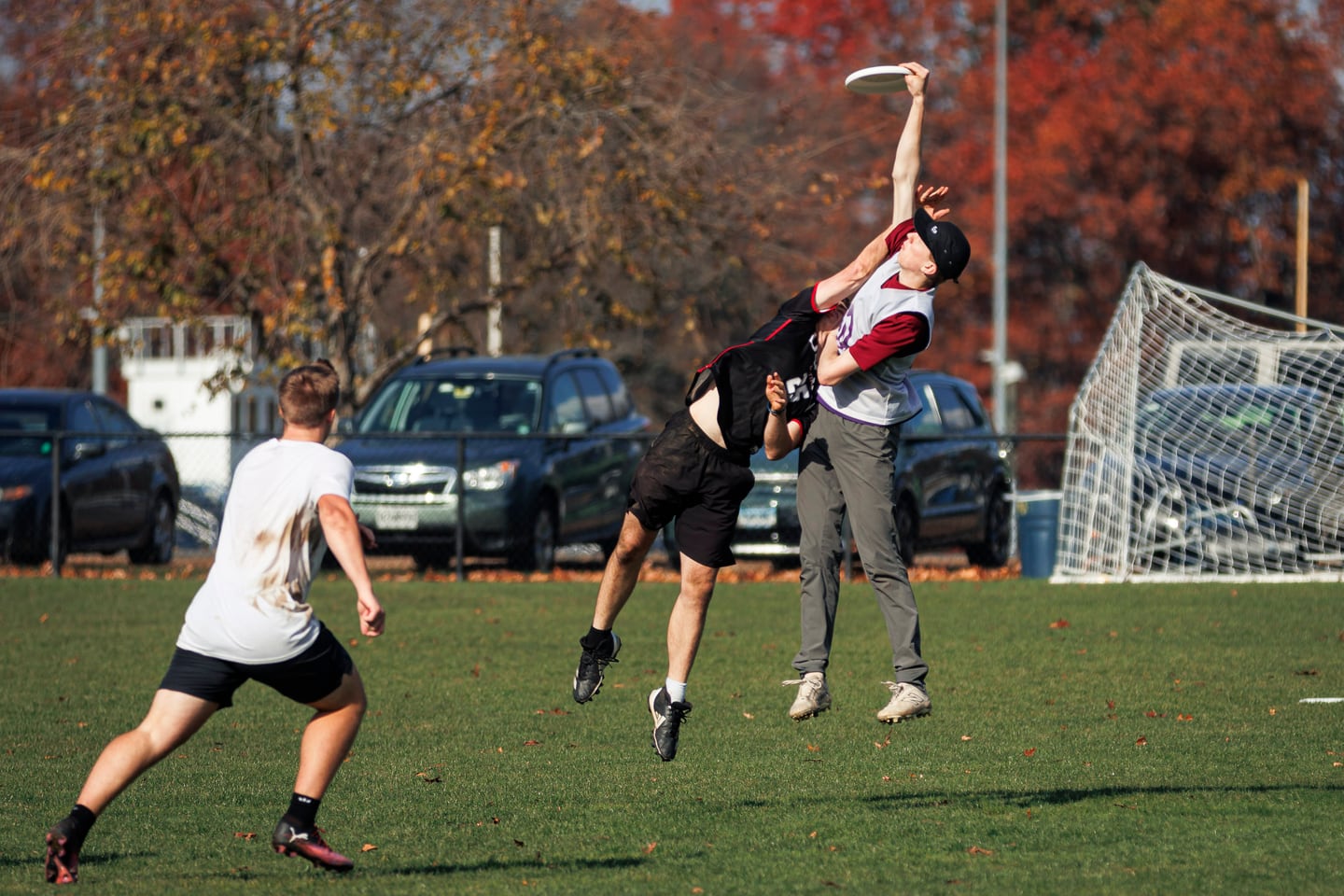 Two players contest a high catch in red and black kits.
