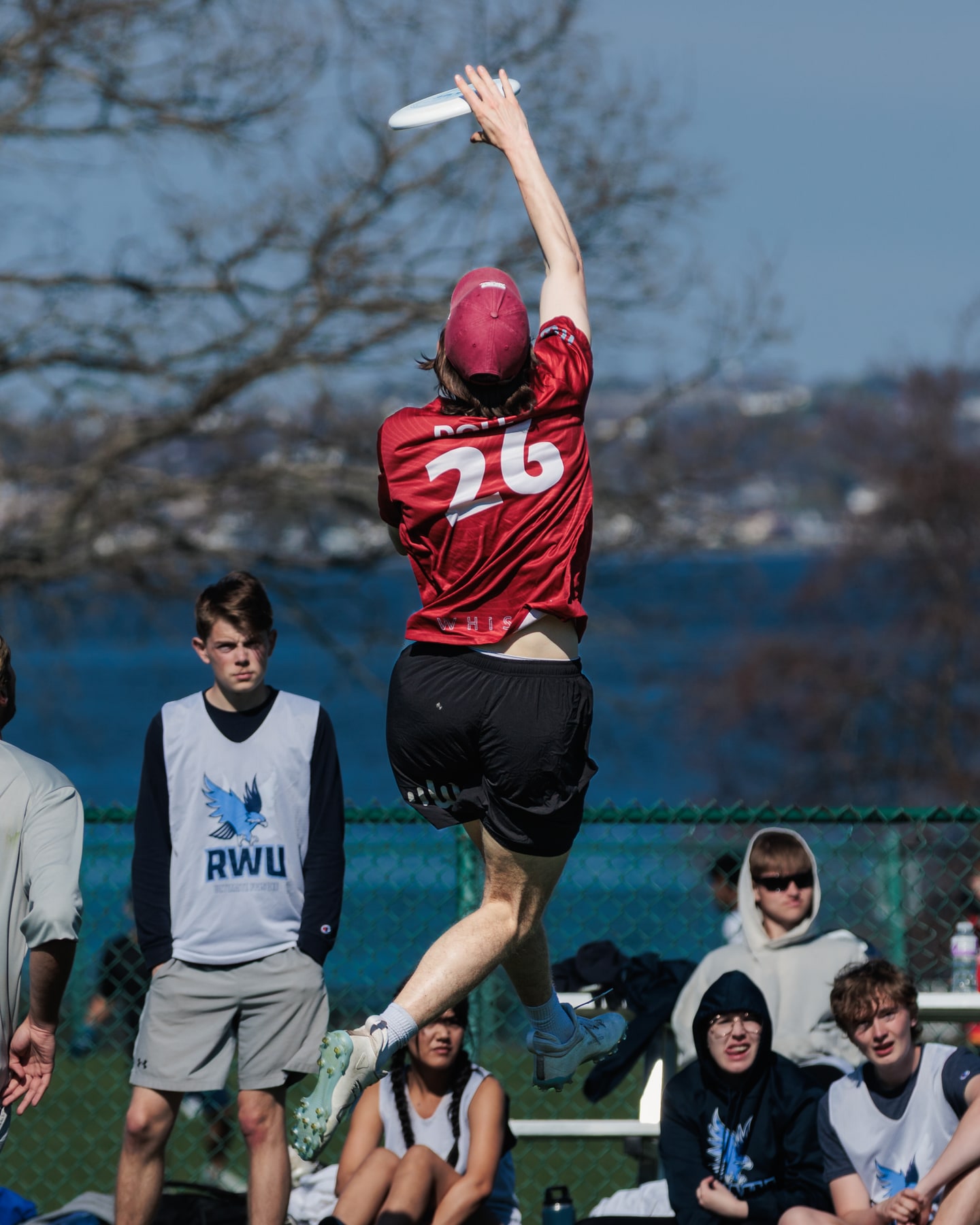 A WPI Whisper player jumps above nearby defenders with one arm extended toward the disc.