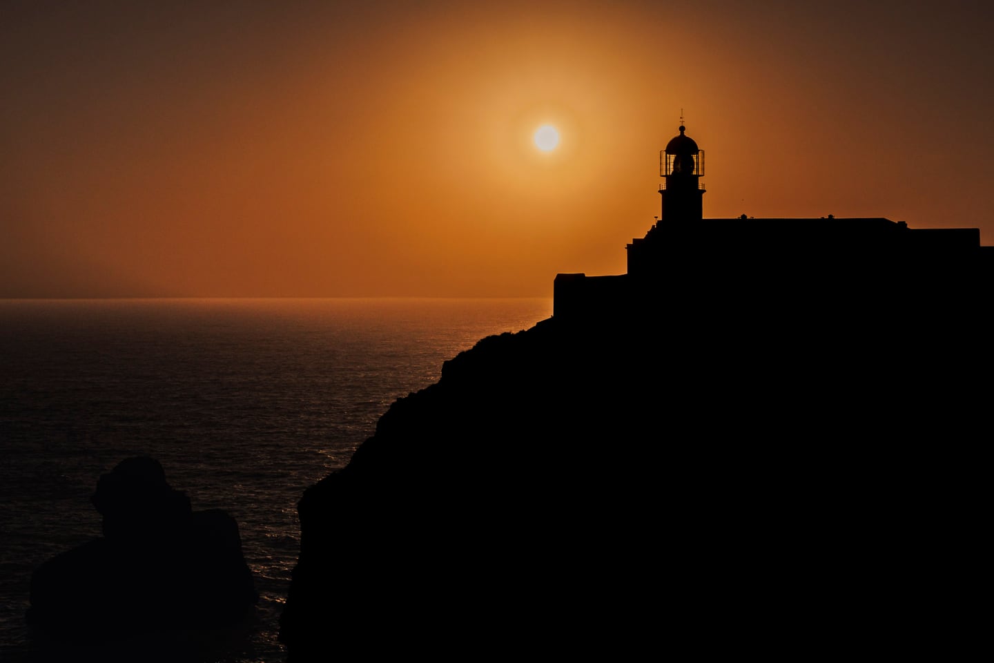 Ocean fortress at sunset with warm sky and blue water.