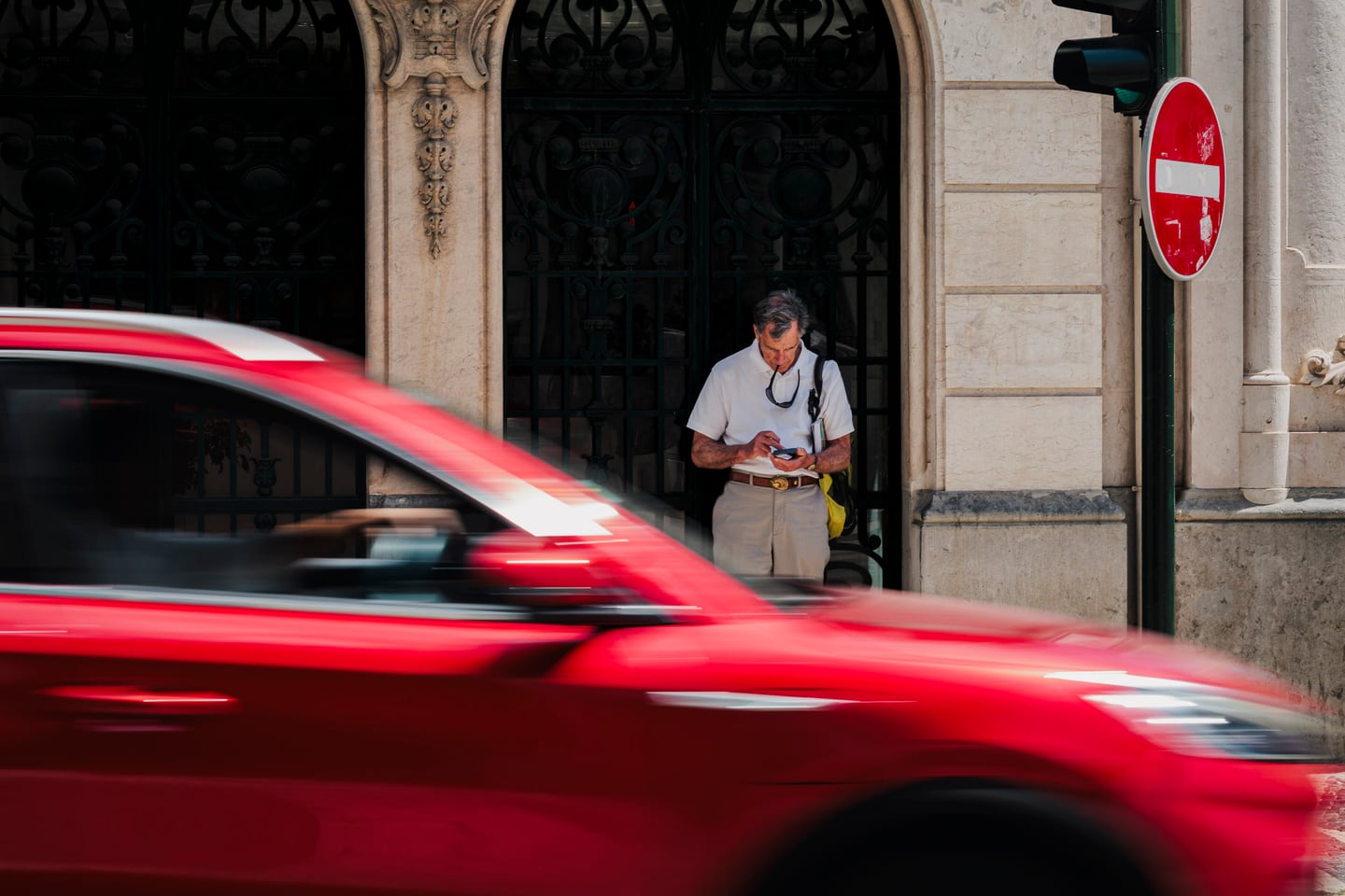 A red car speeding through an urban street.