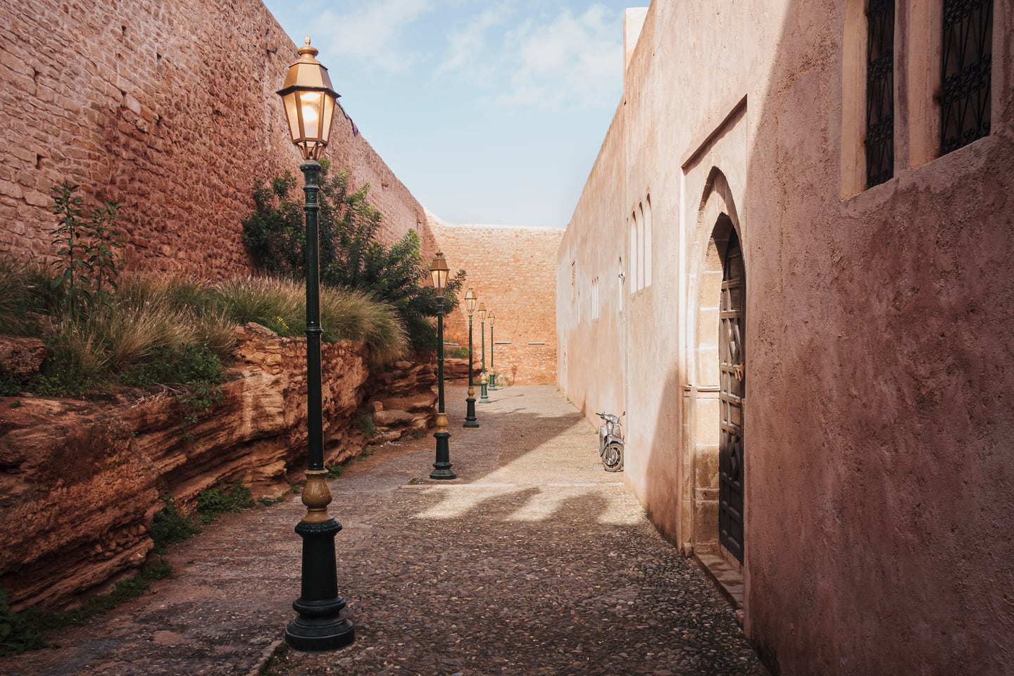 A sunlit alley with warm stone walls and deep shadow.