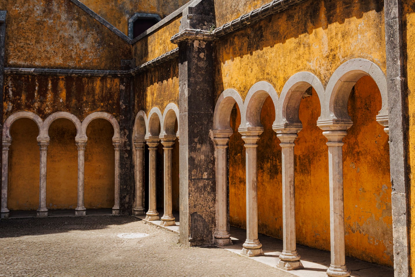 Sunlit yellow arches over a city passage.