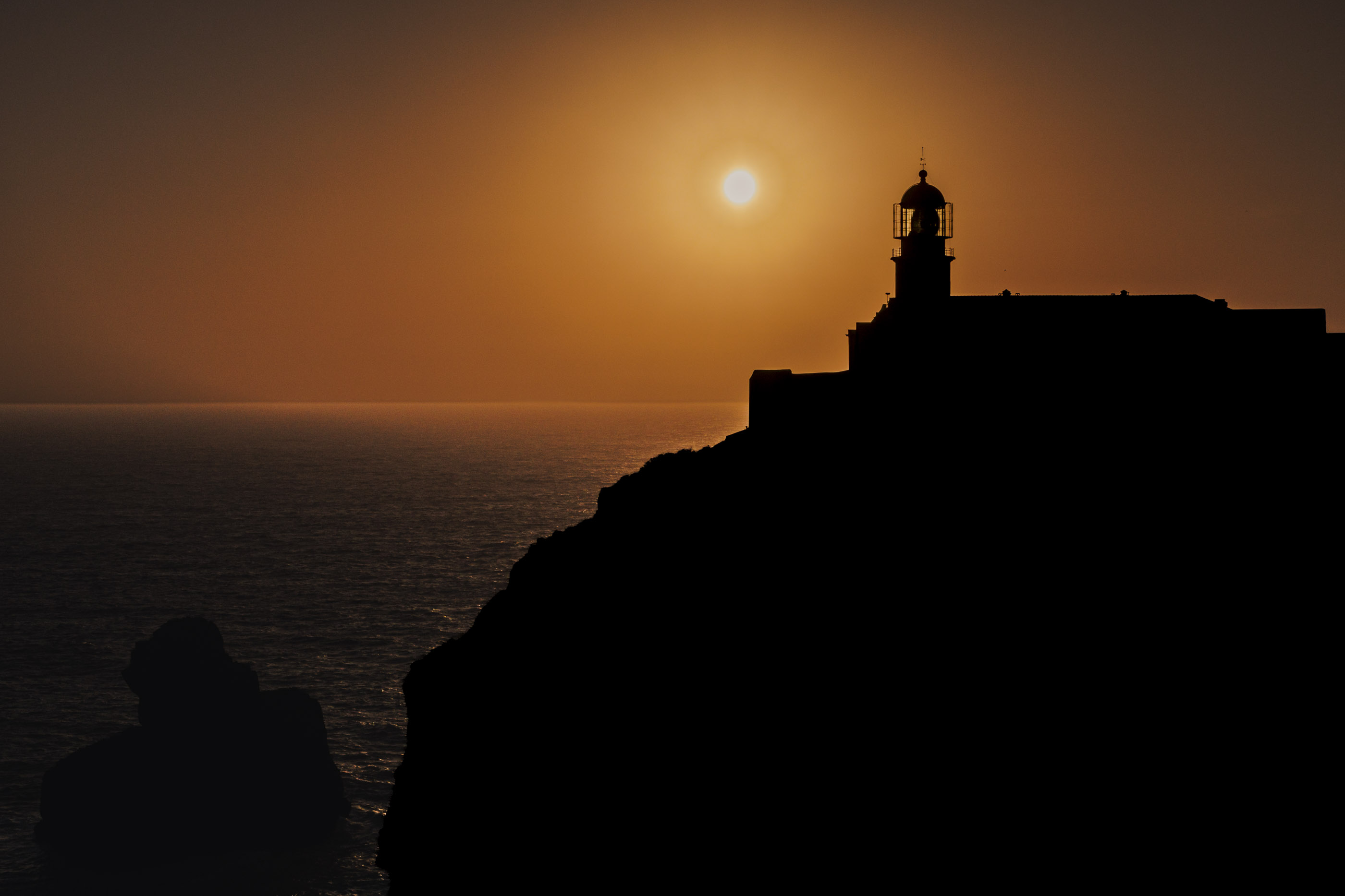 Ocean fortress at sunset with warm sky and blue water.