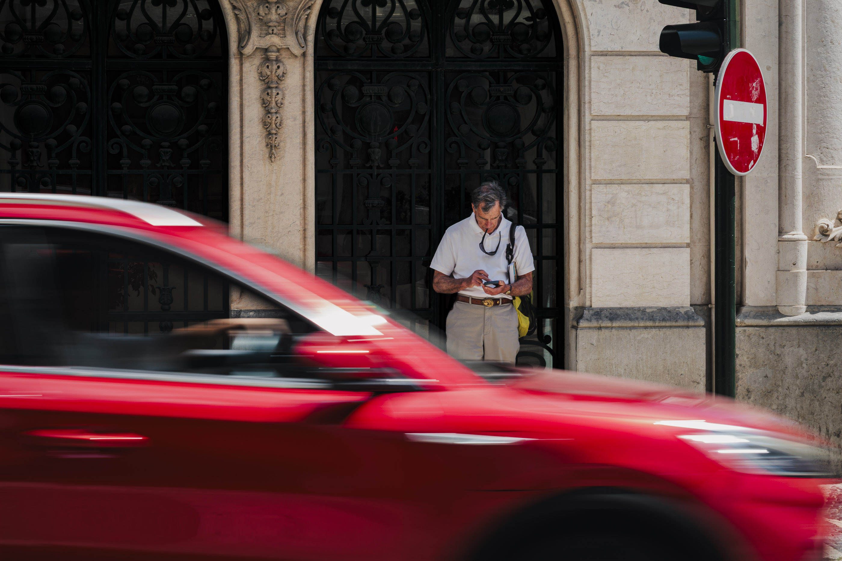 A red car speeding through an urban street.